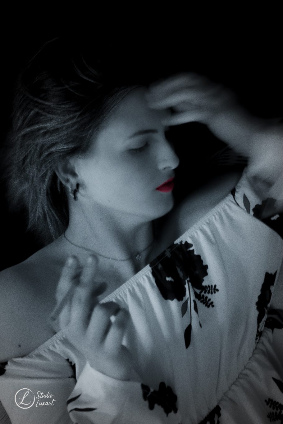 Femme en robes blanches avec des fleurs noires, visage partiellement ombragé et lèvres rouges.